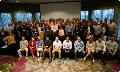 Large group photo of professionals in a conference room.