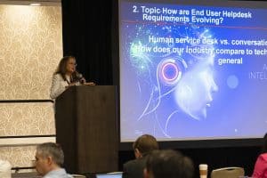 Speaker presenting at a conference with slide.