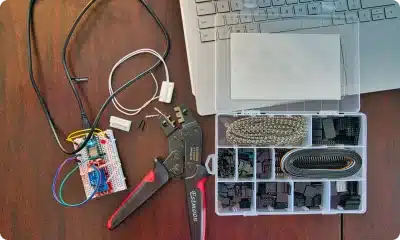 A technical workspace with tools and a laptop on a wooden table.