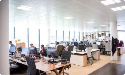 Modern open-plan office with employees working at desks and computers.