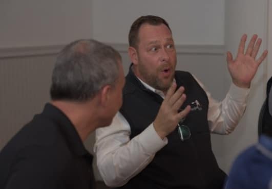 Two men engaged in an animated conversation indoors.